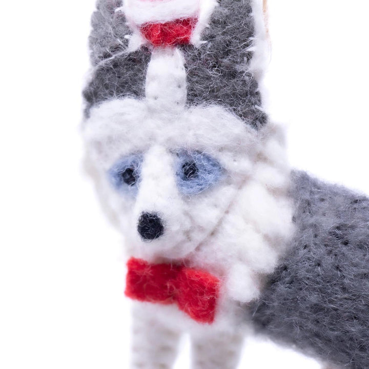 Close-up of a knitted husky with a red bow tie on a white background