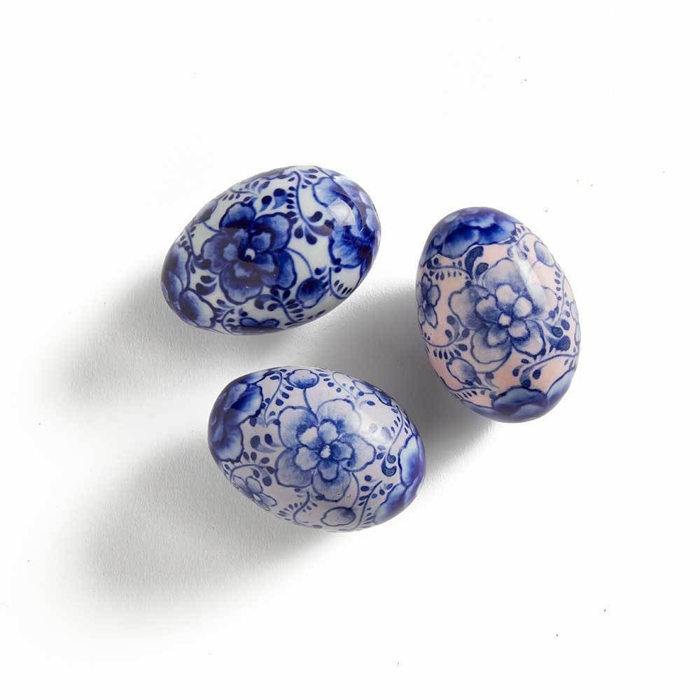 Three ceramic eggs with blue floral patterns on a white background