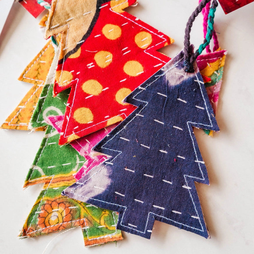 green, red, and blue kantha christmas tree ornaments laid on a white surface