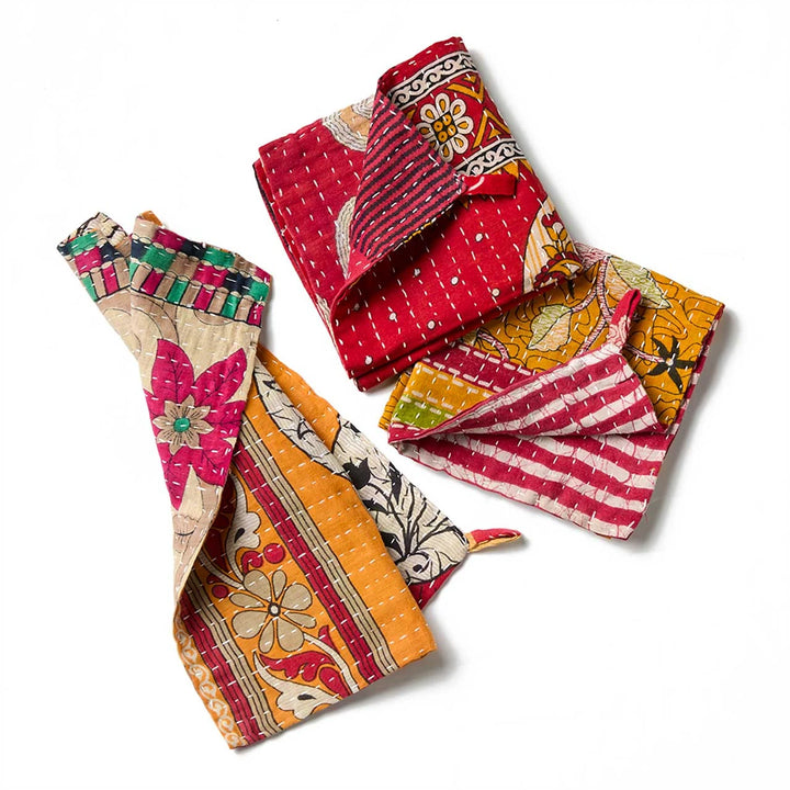 Three folded quilted kantha fabric dishcloths with colorful floral and striped patterns, displayed on a clean white background.
