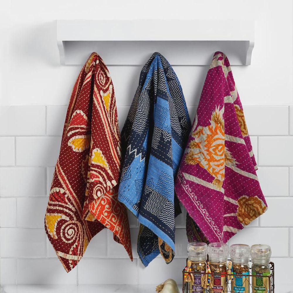 Three Kantha tea towels on a white tile background
