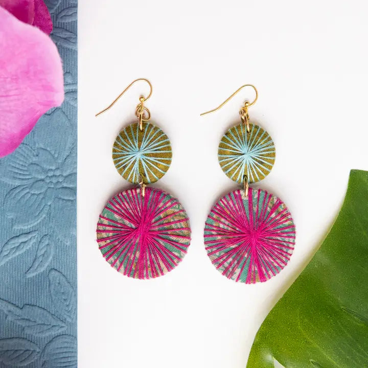 Colorful Kantha earrings with pink and green circular designs on a white background with floral elements.