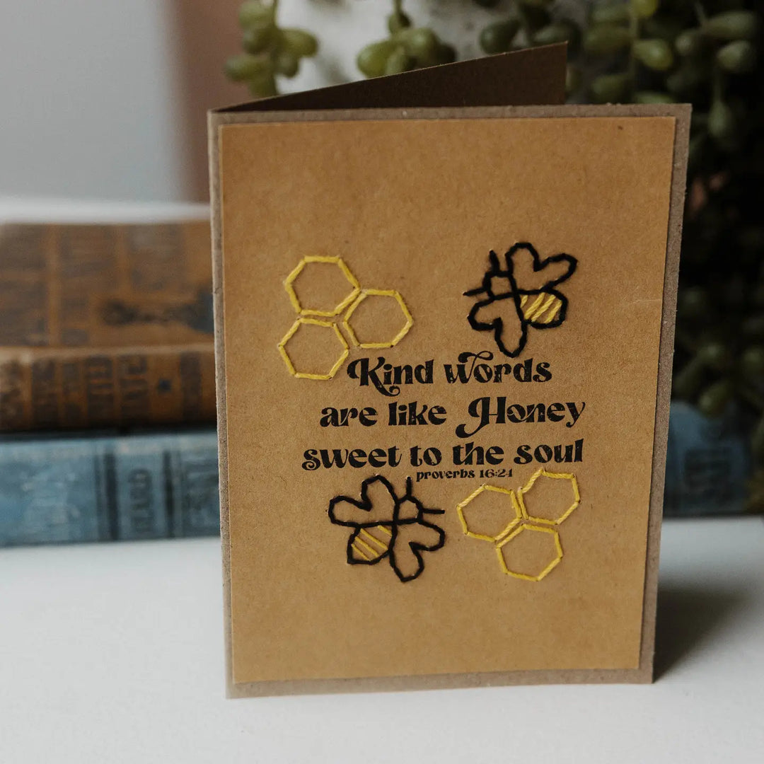 Brown card with embroidered honeycomb designs and text on a white surface.