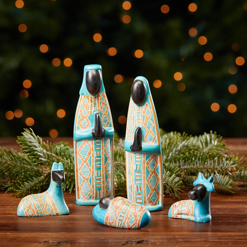 A set of four soapstone nativity figurines in turquoise, orange, and black, including a Mary, Joseph, two sheep and baby Jesus.