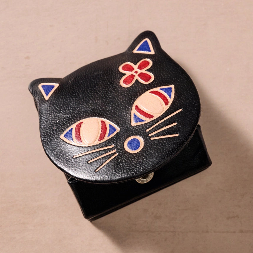 Black cat-shaped pouch with colorful details on a beige background