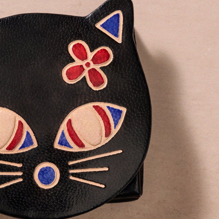 Black cat-shaped pouch with colorful facial features on a beige background