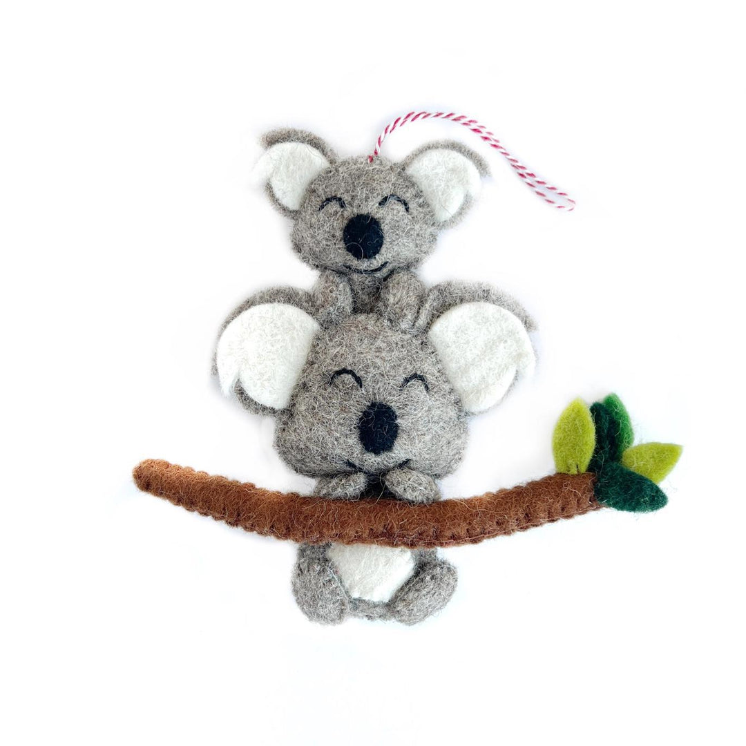 Felt koala ornament on a branch with a white background