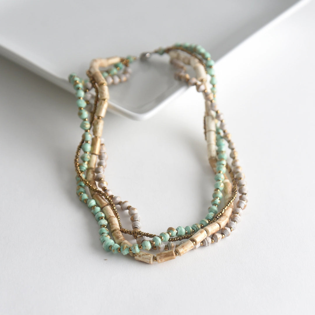 Multistrand beaded necklace with mint and gold tones on a white surface