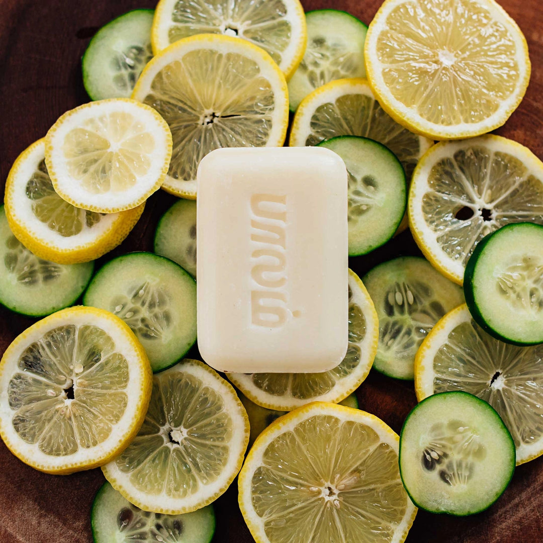 Hand-crafted lemon scented bar of soap on top of sliced lemons and cucumbers.