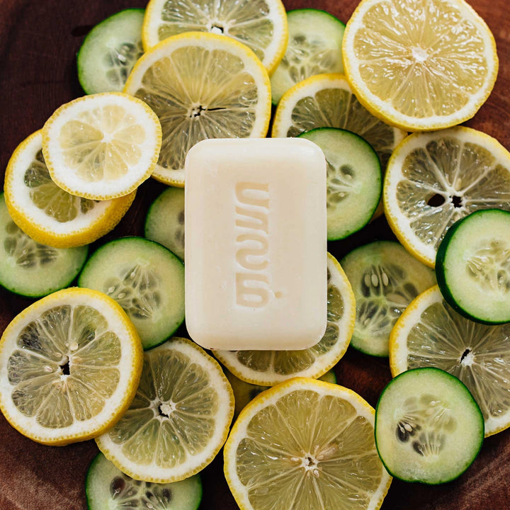 Hand-crafted lemon scented bar of soap on top of sliced lemons and cucumbers.