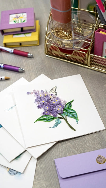 Set of greeting cards with floral design on a desk with stationery items.