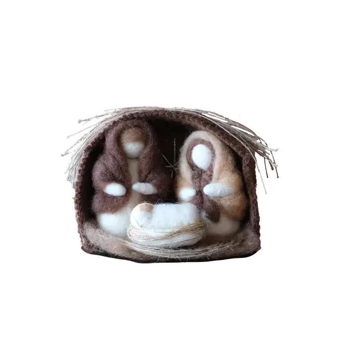 A nativity set featuring the figures of Mary, Joseph, and Baby Jesus within a straw and stable barn backdrop, crafted from wool felt.