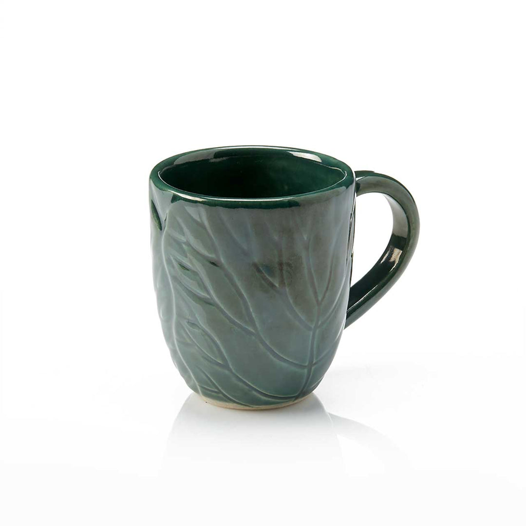 Green ceramic mug with leaf pattern on a white background