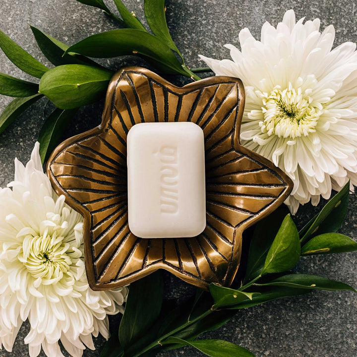 Hand-crafted lotus soap bar on soap dish with white lotus flowers