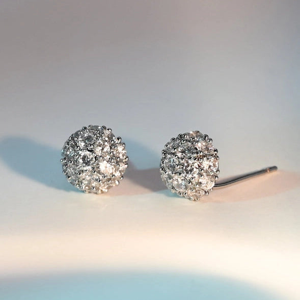 Pair of silver stud earrings with clear gemstones on a light background