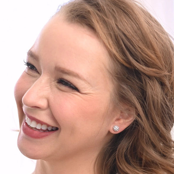 Woman with a side part hairstyle wearing a white top against a plain background