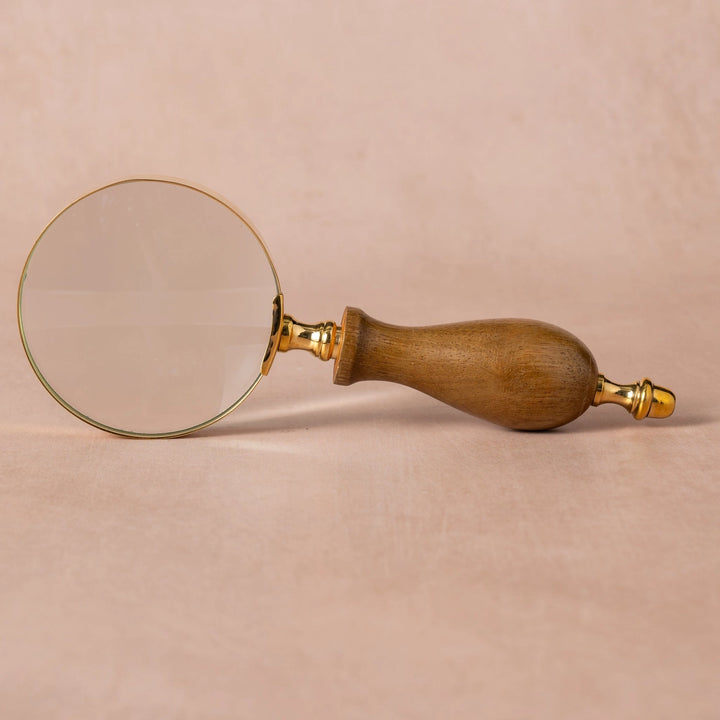 Wooden-handled magnifying glass on a beige background