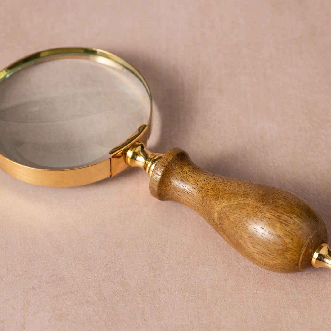 Magnifying glass with wooden handle on a beige background