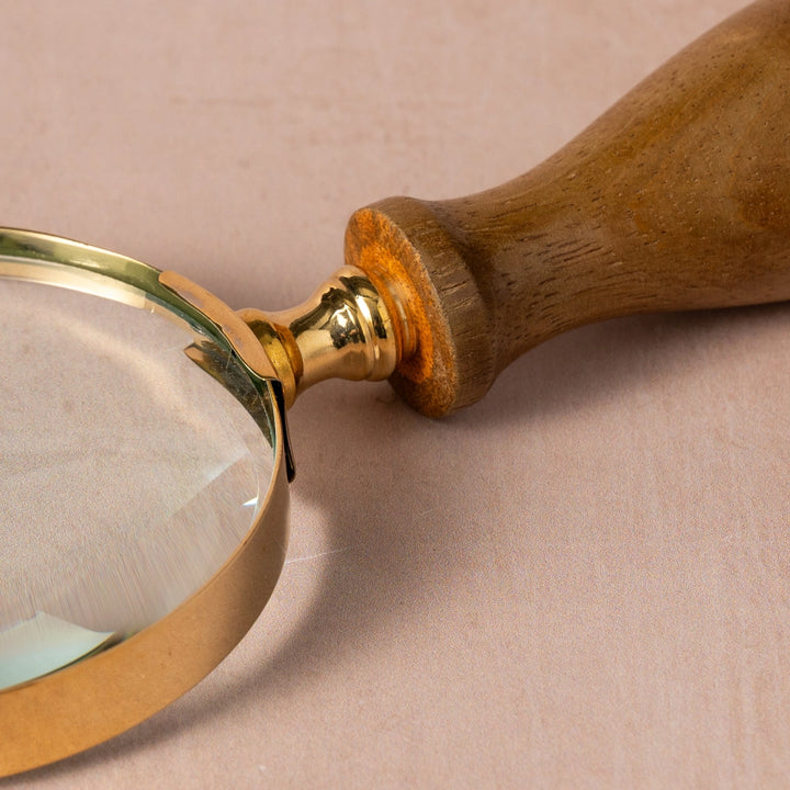 Magnifying glass with wooden handle on a beige background