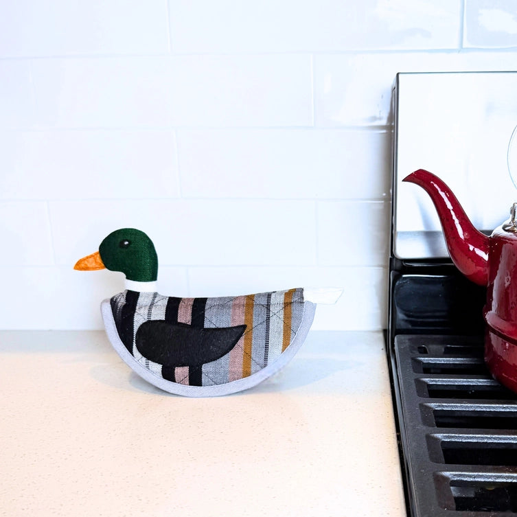Decorative duck-shaped pot holder on a white surface with a tiled wall background