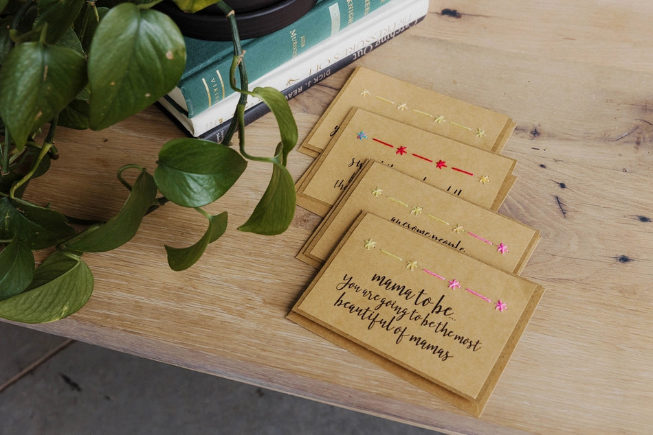 Set of cards with decorative text on a wooden surface with a plant and books in the background