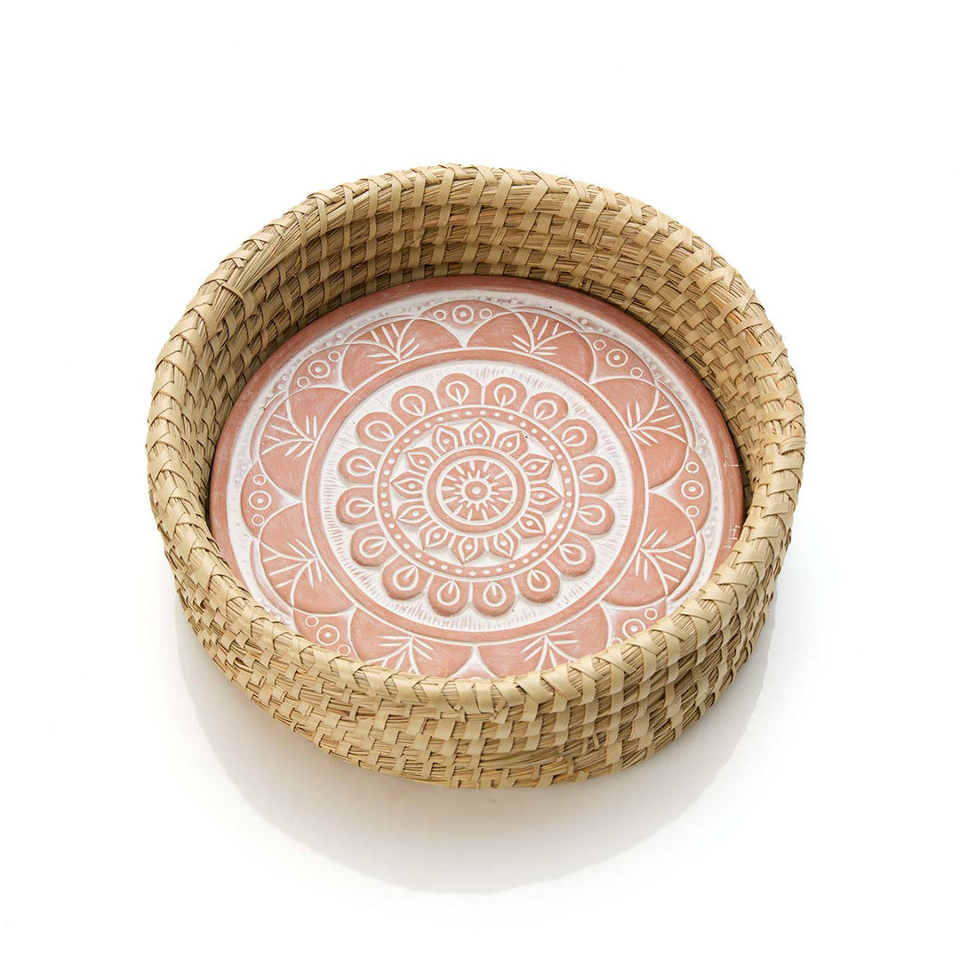 Round woven basket with a terracotta mandala design on a white background