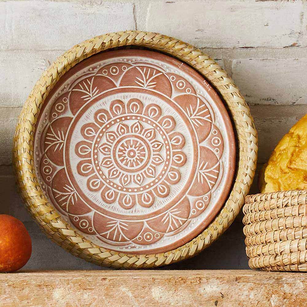 Decorative terracotta plate with mandala design on a wooden surface