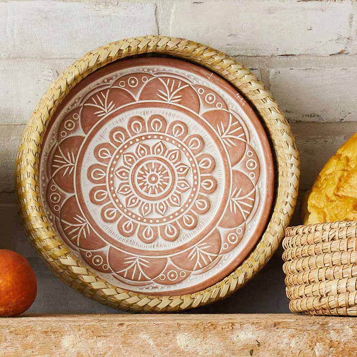 Decorative terracotta plate with mandala design on a wooden surface