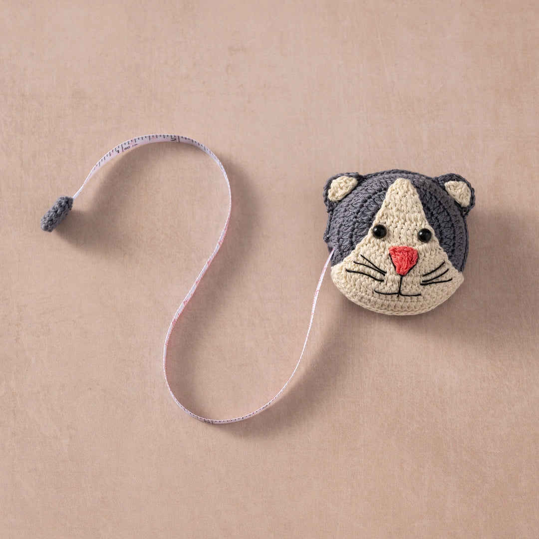 Crocheted cat-shaped measuring tape on a beige background
