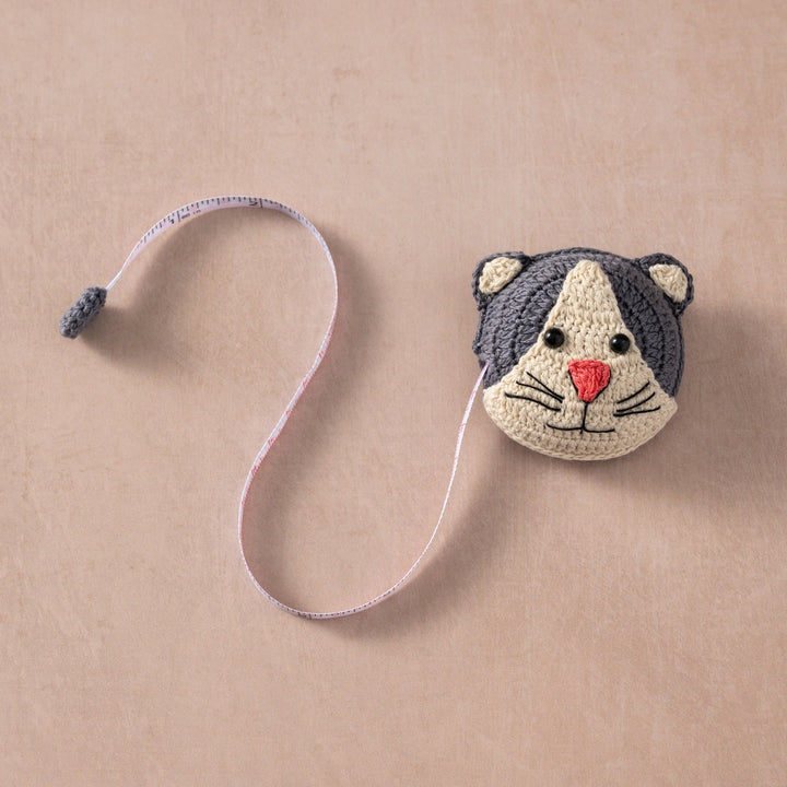 Crocheted cat-shaped measuring tape on a beige background