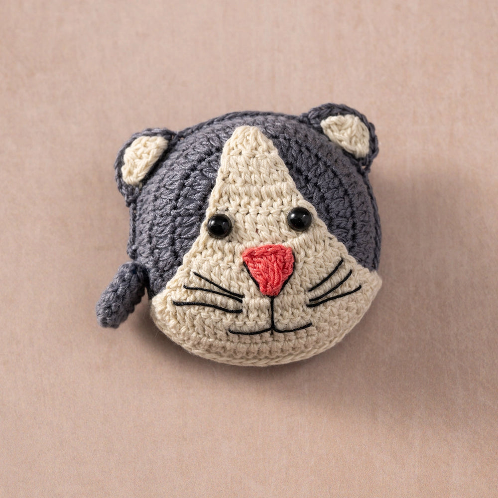 Crocheted cat measuring tape on a beige background