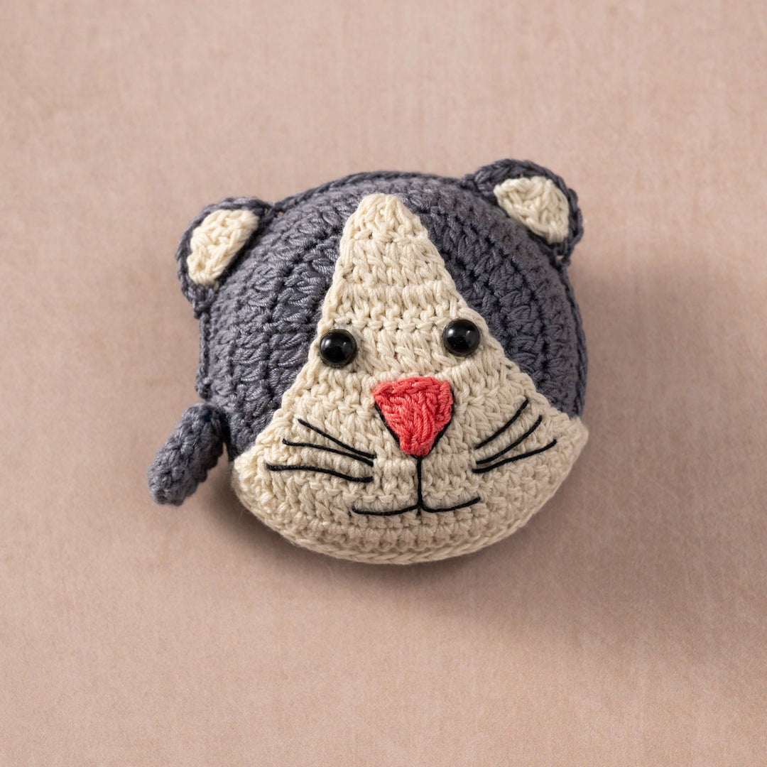 Crocheted cat measuring tape on a beige background
