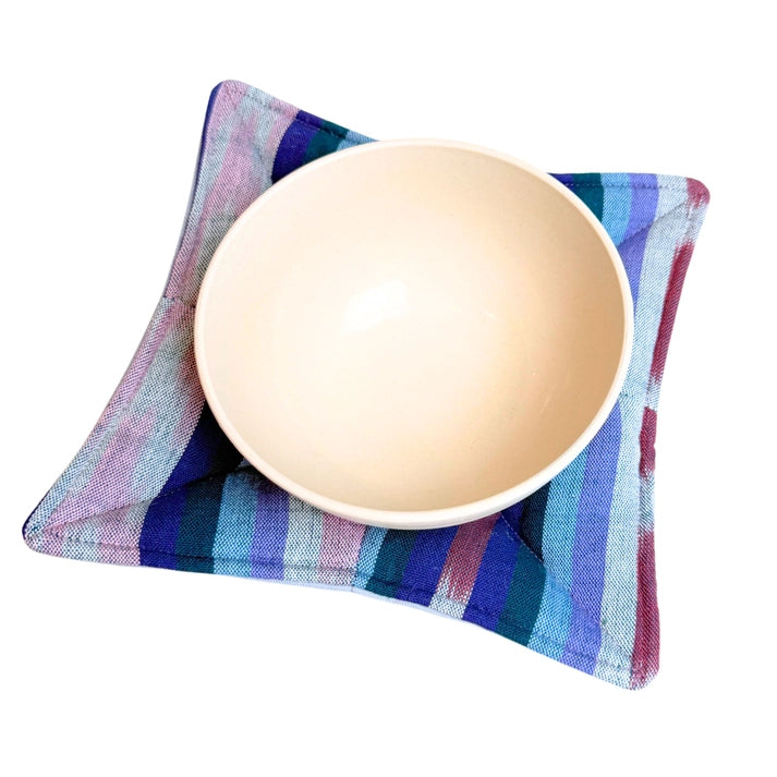 Beige ceramic bowl on a colorful striped fabric bowl cozy