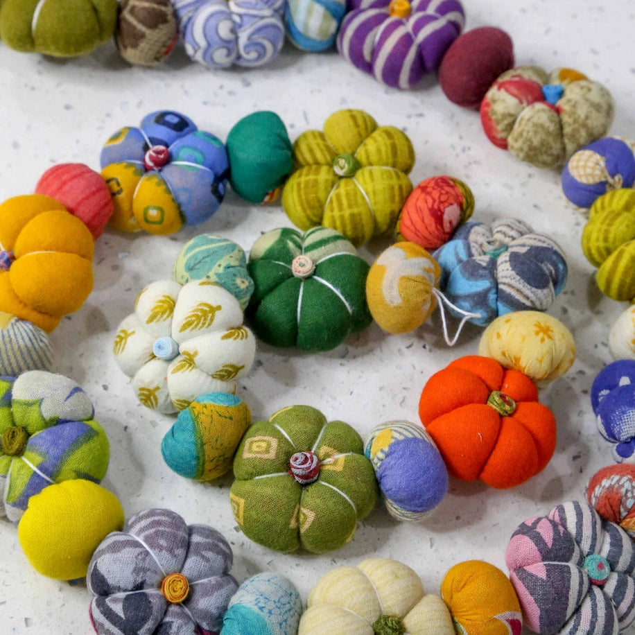 Colorful fabric pumpkins and flowers on a white surface