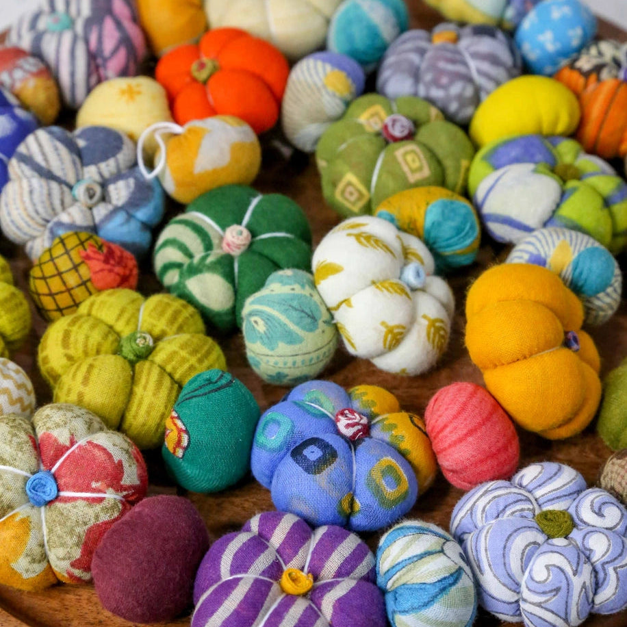 Colorful fabric pumpkins and gourds on a wooden plate