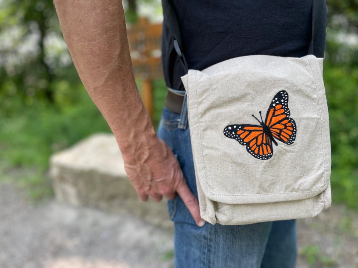 Person holding a beige bag with a butterfly design outdoors