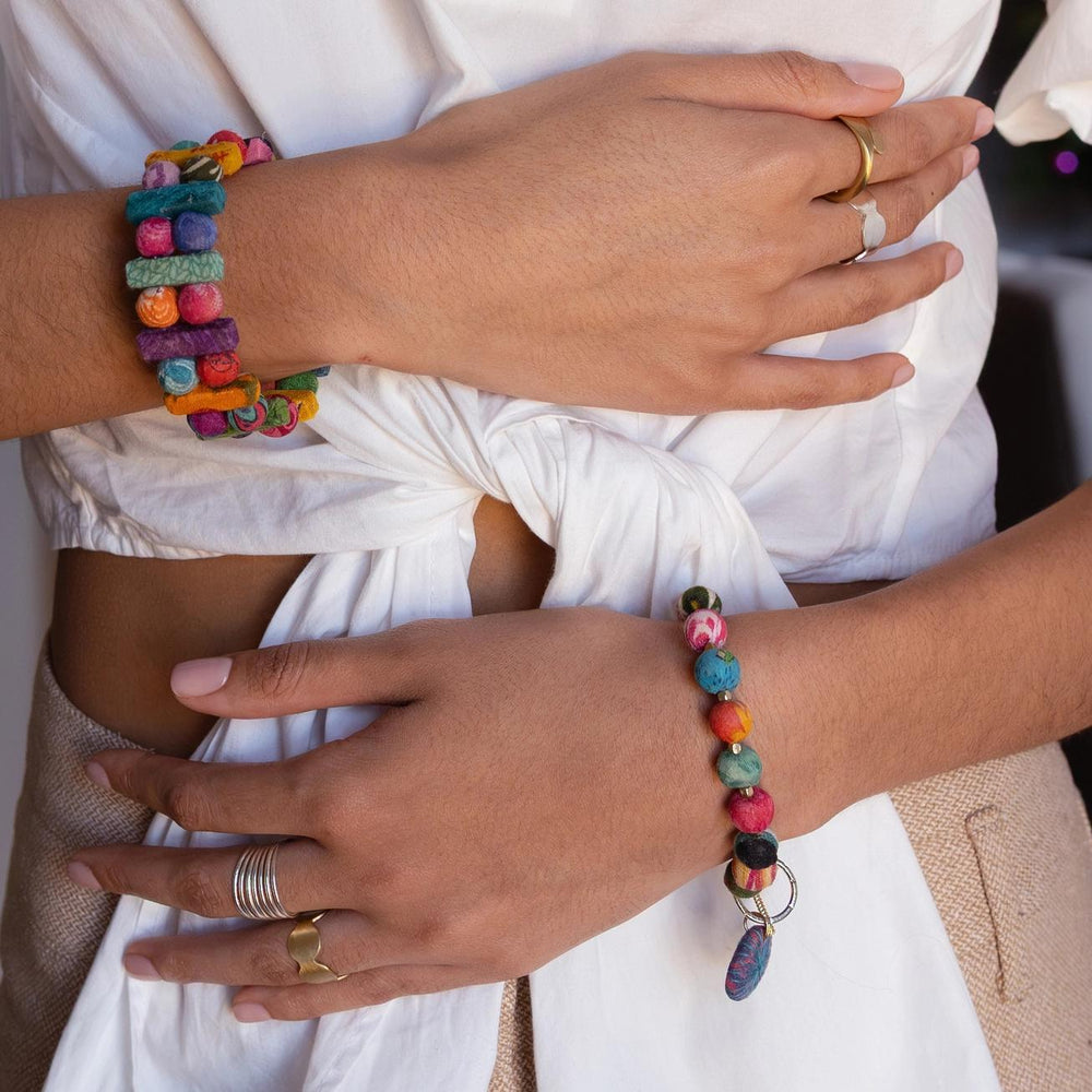 Close-up of hands wearing colorful beaded bracelets and rings.