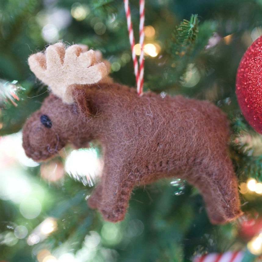 Brown moose ornament hanging on a Christmas tree with blurred lights in the background