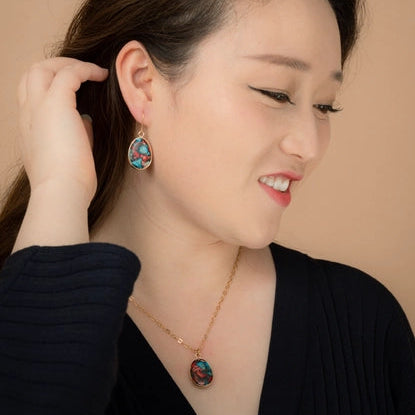 Woman wearing earrings and a necklace against a beige background