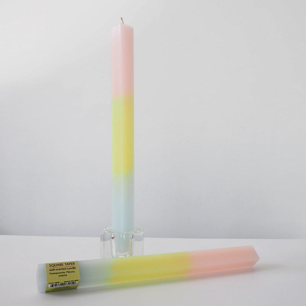 Colorful candle with a gradient from pink to yellow on a white background