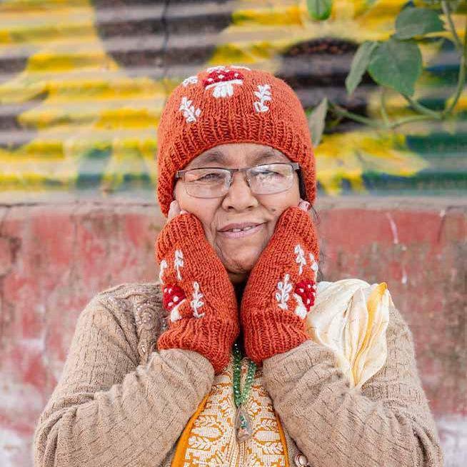 Person wearing a red knitted hat and mittens with a colorful background