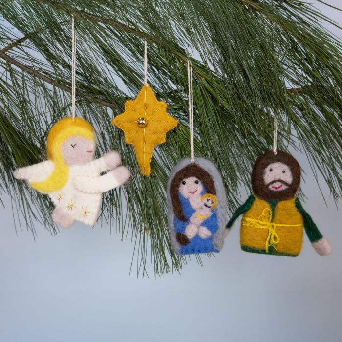 Felt nativity scene ornaments hanging on a Christmas tree.