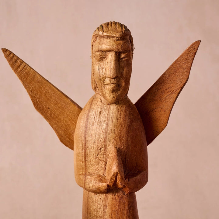 A hand-carved wooden angel figurine with outstretched wings and a praying pose, shown against a plain beige background.