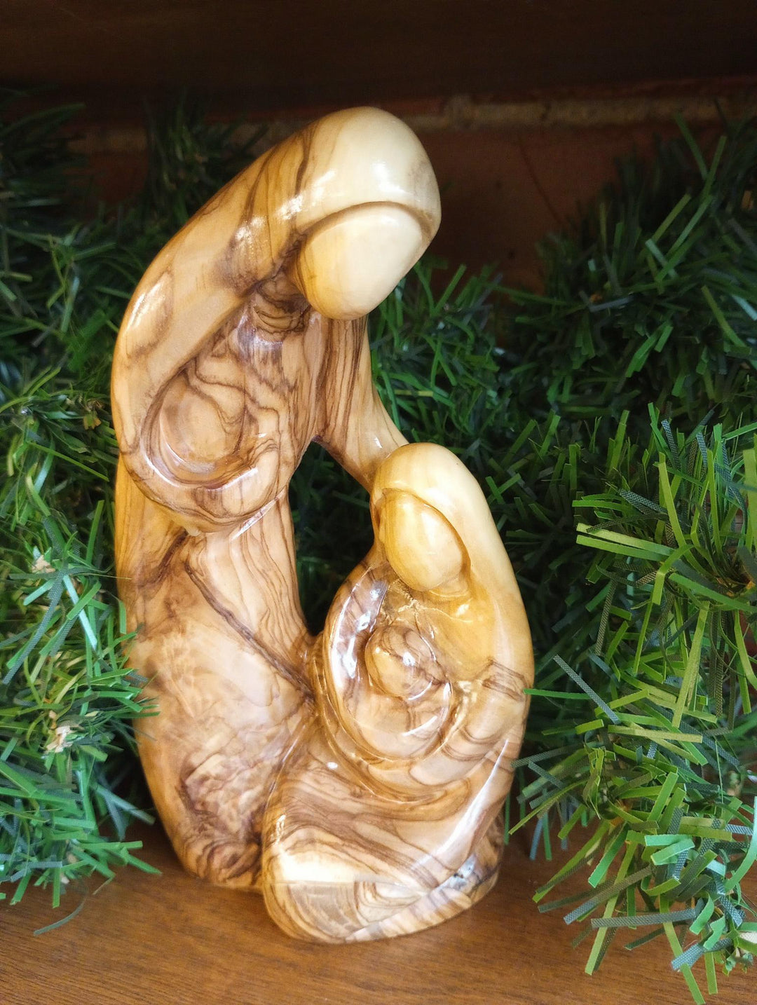 olive wood nativity on a wood background with greenery