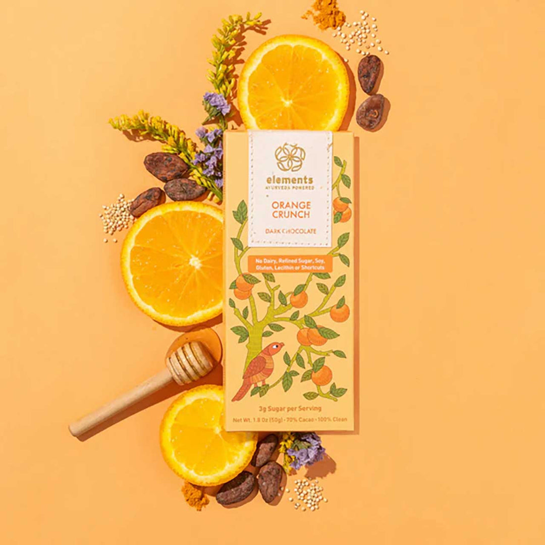 Chocolate bar packaging with orange Crunch flavor surrounded by oranges, honey, and flowers on an orange background