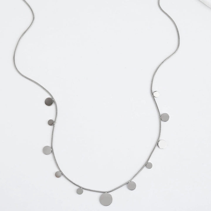 A silver necklace with silver disks on a white background
