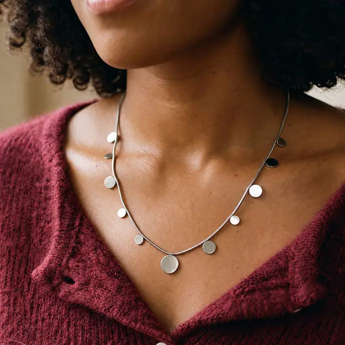 A woman wearing a silver necklace with silver disks.