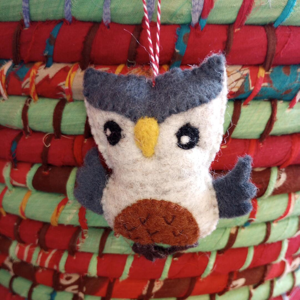 Felt owl ornament on a stack of colorful fabric rolls