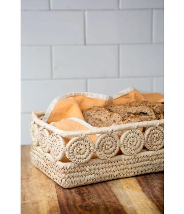 Woven basket with bread on a wooden surface and tiled wall background