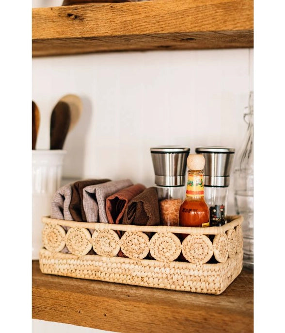 Woven basket with kitchen items on a wooden shelf